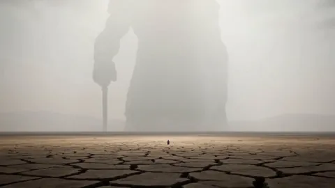 A colossal statue looms over a tiny man in the dream